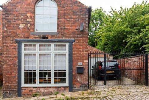 a brick house with a white window and a black fence at Character Cottage with Private Parking in Central Leeds, Near LGI in Leeds
