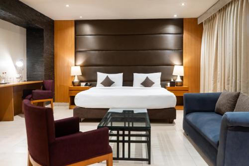 a hotel room with a bed and two chairs at Udman Hotel Panchshila Park in New Delhi