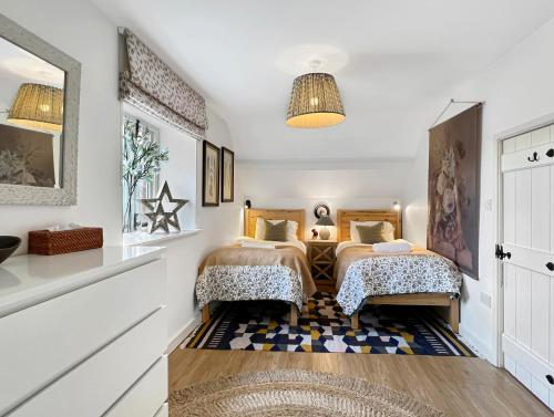 a bedroom with two beds and a rug at The Stables Lydeard St Lawrence in Combe Florey