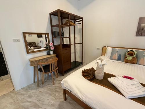 a bedroom with a bed with a table and a mirror at Khaolak Beachhouse Kelolo in Khao Lak