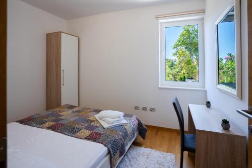 a bedroom with a bed and a desk and a window at My Nest Accommodation in Privlaka