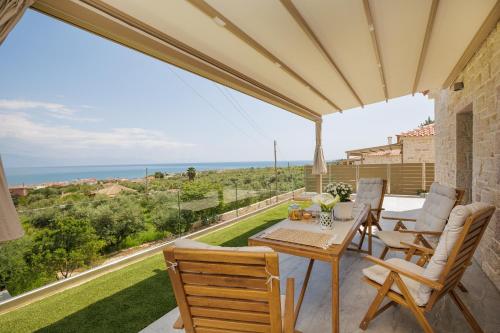 a patio with a table and chairs and a view of the ocean at Petra & Thea Chrani Villas in Chrani