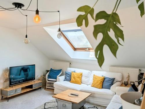 a living room with a white couch and a tv at Feel at Home - à 2 pas de la voie Verte & Meuse in Braux