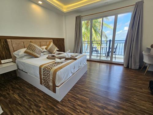 a bedroom with a bed with a view of the ocean at Alma Maldiva, Beach Hotel in Ariyaddu