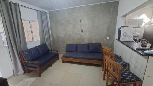 a living room with a blue couch and chairs at Casa 2 minutos a pé da Praia de INDAIÁ in Bertioga
