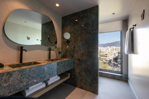 a bathroom with a large marble sink and a large mirror at Golden Age Athens Hotel in Athens