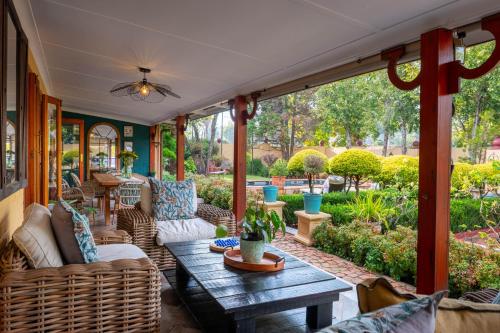 a screened porch with a table and wicker furniture at Hampton House Guest House in Centurion