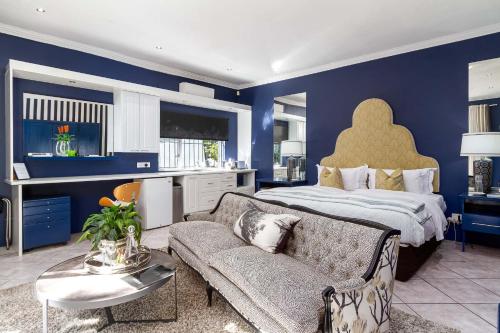 a blue bedroom with a bed and a couch at Life & Leisure Boutique Guesthouse in Stellenbosch