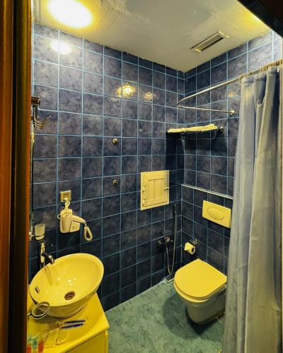 a blue tiled bathroom with a toilet and a sink at Crossway Hotel Baku in Baku