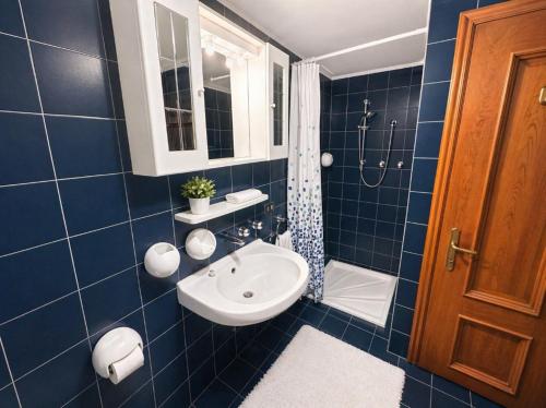 a blue tiled bathroom with a sink and a shower at La Casa del Mare in Caorle