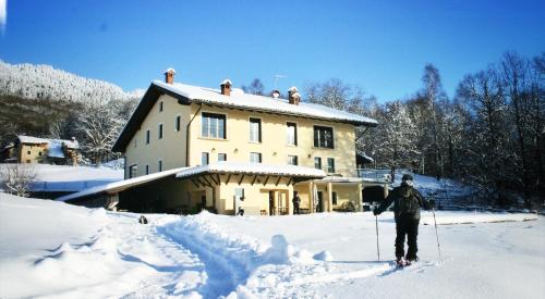a person on skis in the snow in front of a house at Cascina il Faggio Country House in Mosso Santa Maria