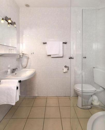a white bathroom with a toilet and a sink at Strandhotel Deichläufer in Butjadingen