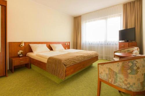 a bedroom with a bed and a large window at Strandhotel Deichläufer in Butjadingen