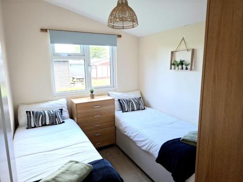 two beds in a small bedroom with a window at Cosy Corner Cabin in Saint Merryn