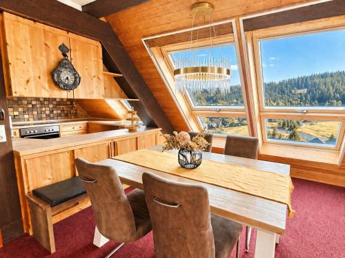 a kitchen with a wooden table and chairs and windows at Ferienhaus mit 3 Apartments - Belle Apartment - Top-Lage, Sauna, HS-Card in Feldberg