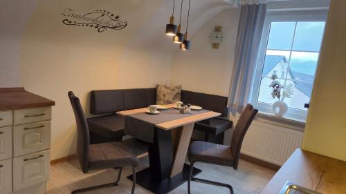 a dining room with a table and chairs and a window at Panoramaferienwohnung Bergwiese in Masserberg