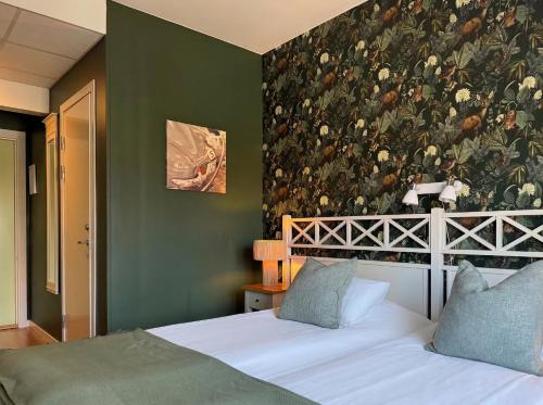 a bedroom with two beds and a wall with a bird wallpaper at Hotell Nostalgi in Motala
