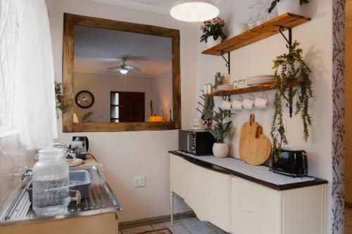 a kitchen with a counter with a sink and a mirror at The Hidden Garden Guesthouse in Meyerton