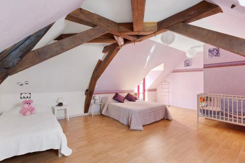 a attic bedroom with two beds and a crib at Gîte La Clématite in Mosnes