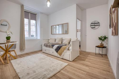 a white bedroom with a bed and a table at L'intemporel in Périgueux