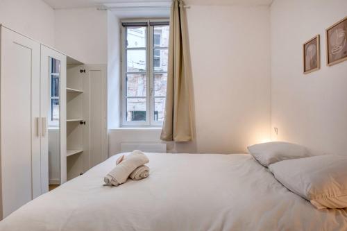 a bedroom with a white bed with a towel on it at L'intemporel in Périgueux