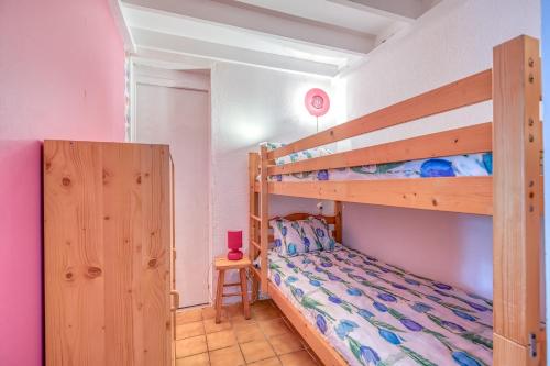 a bedroom with two bunk beds and a table at Lacanau Océan avec jardin in Lacanau-Océan