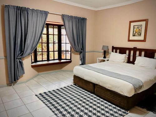a bedroom with a bed and a window at Phumulani Lodge Kameeldrift in Pretoria