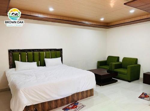 a bedroom with a bed and two green chairs at Brown oak farms in Sohna