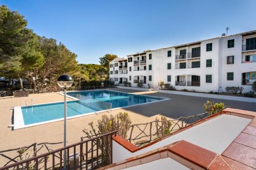 an apartment with a swimming pool in front of a building at Complejo turístico Menorca SOL ISLA in Arenal d'en Castell
