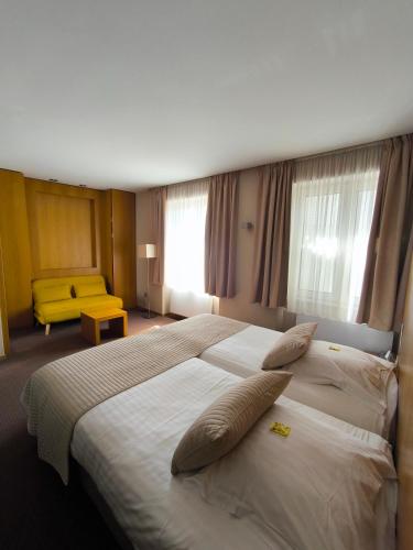 a hotel room with two beds and a yellow couch at Aux Deux Clefs - Hôtel Restaurant Groff in Biesheim