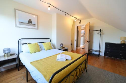 a bedroom with a large bed with yellow pillows at Suffolk Coast Townhouse in Pakefield