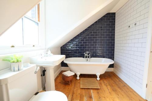 a bathroom with a white tub and a sink at Suffolk Coast Townhouse in Pakefield