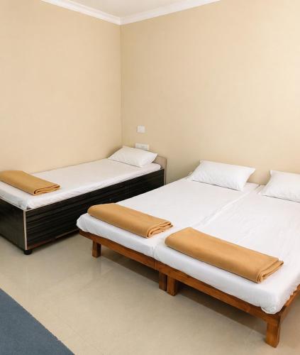 two beds in a room with white walls at vishranti bhawan in Dwarka