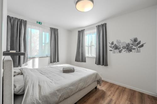 a bedroom with a bed and two windows at vakantiewoning T'is ier goed in Jabbeke
