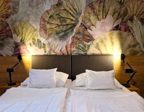 two beds in a room with a mural on the wall at Garda Hotel in Szombathely