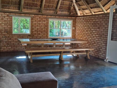 a picnic table in a brick room with two windows at Buck Hill Bush Lodge in Magaliesburg