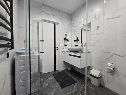 a white bathroom with a sink and a shower at Belvedere Apart, parking in Ivano-Frankivsk