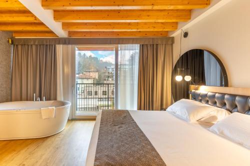 a bedroom with a tub and a bed and a window at Hotel Master in Brescia