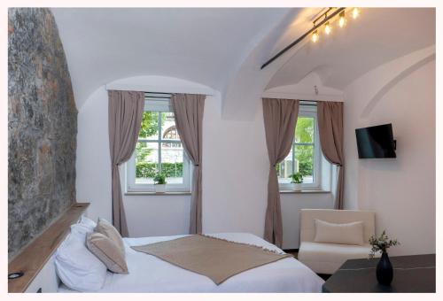 a bedroom with a bed and two windows at The 1826 Residence in Ljubljana