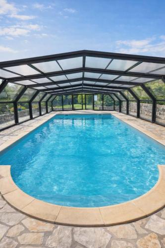 a large pool with a metal roof at Gite le Martalou in Lacapelle-Viescamp