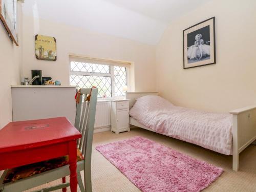 a bedroom with a bed and a red desk at Daisy Cottage in Dorking