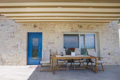 a wooden table and chairs on a patio with a blue door at Petra & Thea Chrani Villas in Chrani