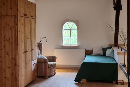 a bedroom with a bed and a chair and a window at Atelier - Flensburger Förde in Westerholz