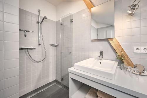 a white bathroom with a sink and a shower at Hay Loft - Flensburger Förde in Westerholz