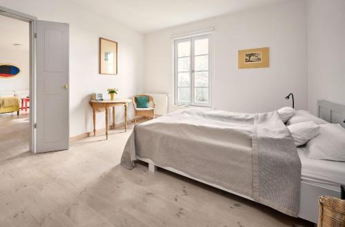 a white bedroom with a bed and a table at Hay Loft - Flensburger Förde in Westerholz