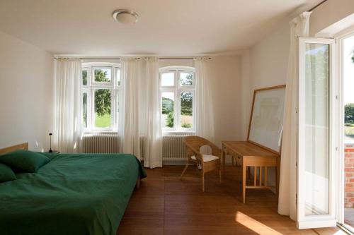 a bedroom with a bed and a desk and windows at Lake View - Flensburger Förde in Westerholz
