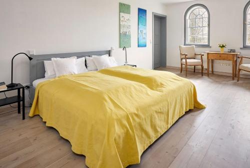 a bedroom with a bed with a yellow blanket on it at Rose Garden - Flensburger Förde in Westerholz