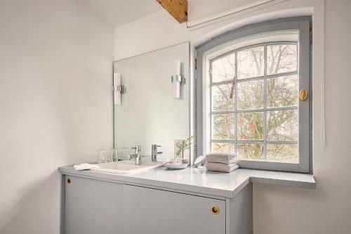 a white bathroom with a sink and a window at Rose Garden - Flensburger Förde in Westerholz