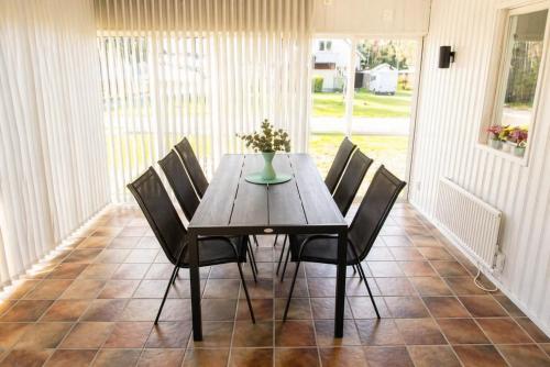 a dining room table with chairs and a vase of flowers at Only 150 m to the nearest lake and 2,5 km to the top of Isaberg in Hestra