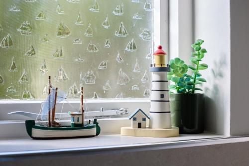 a toy lighthouse and a boat on a window sill at Coastguards in Southwold